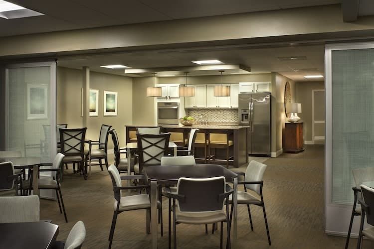 A modern kitchen and dining area with tables and chairs, featuring contemporary lighting and appliances.