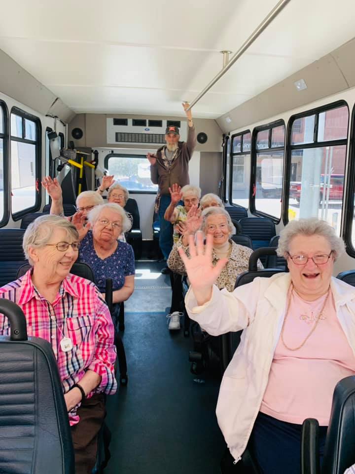 A group of smiling seniors enjoying a bus ride together.