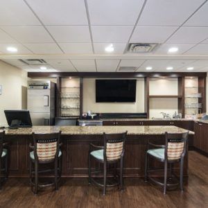 Modern bar area with a counter and seating, featuring a television on the wall.