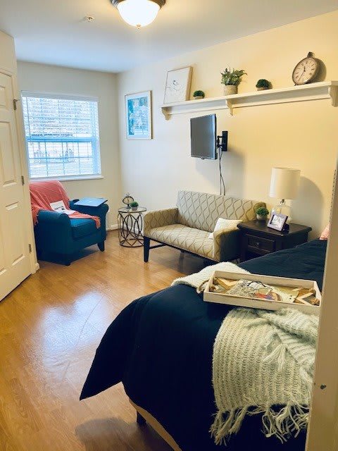A cozy bedroom with a small sofa, wall-mounted TV, and decorative elements.