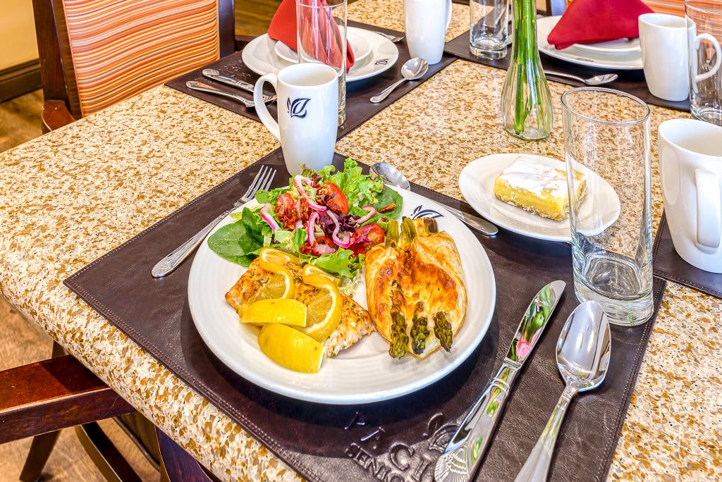 A well-presented breakfast with an omelette, salad, croissant, and a cup of coffee on a neatly set dining table.