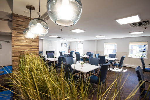 A modern dining area featuring stylish furniture, elegant lighting, and touches of greenery.
