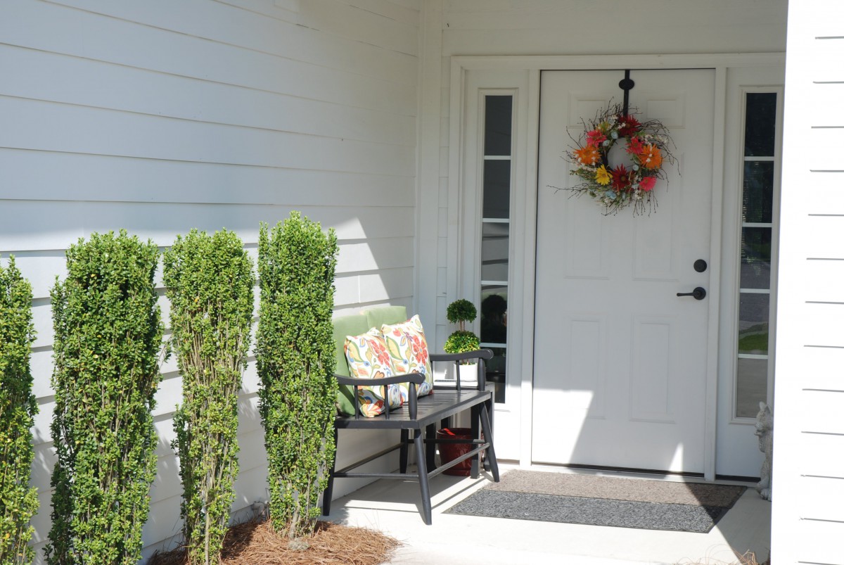 A welcoming front porch with a bench, plants, and a decorative wreath on the door.