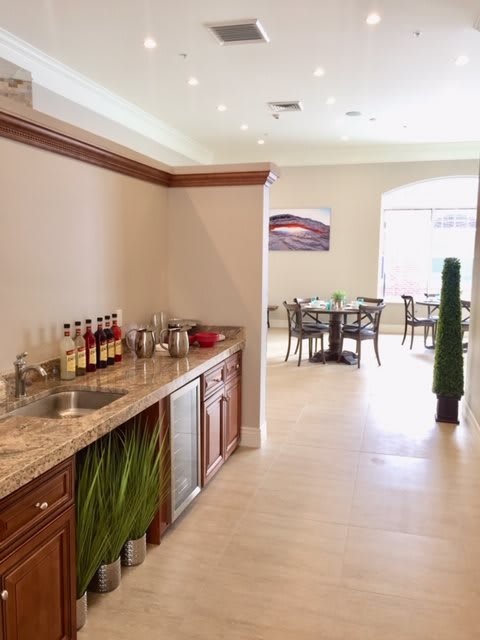 A modern kitchen and dining area with a sleek countertop, bar setup, and wooden cabinets.