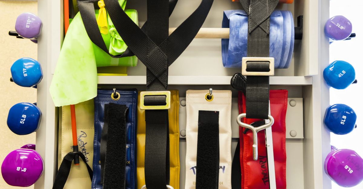 A variety of colorful belts and straps hanging on a wall.