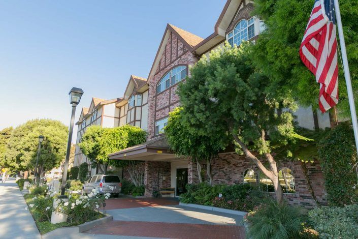 A picturesque hotel with Tudor-style architecture surrounded by trees.