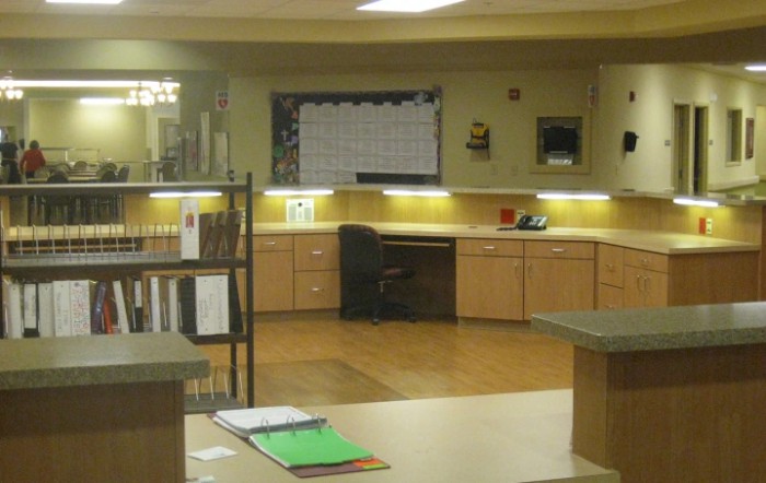 An empty office workspace with a desk, chair, and cabinets.