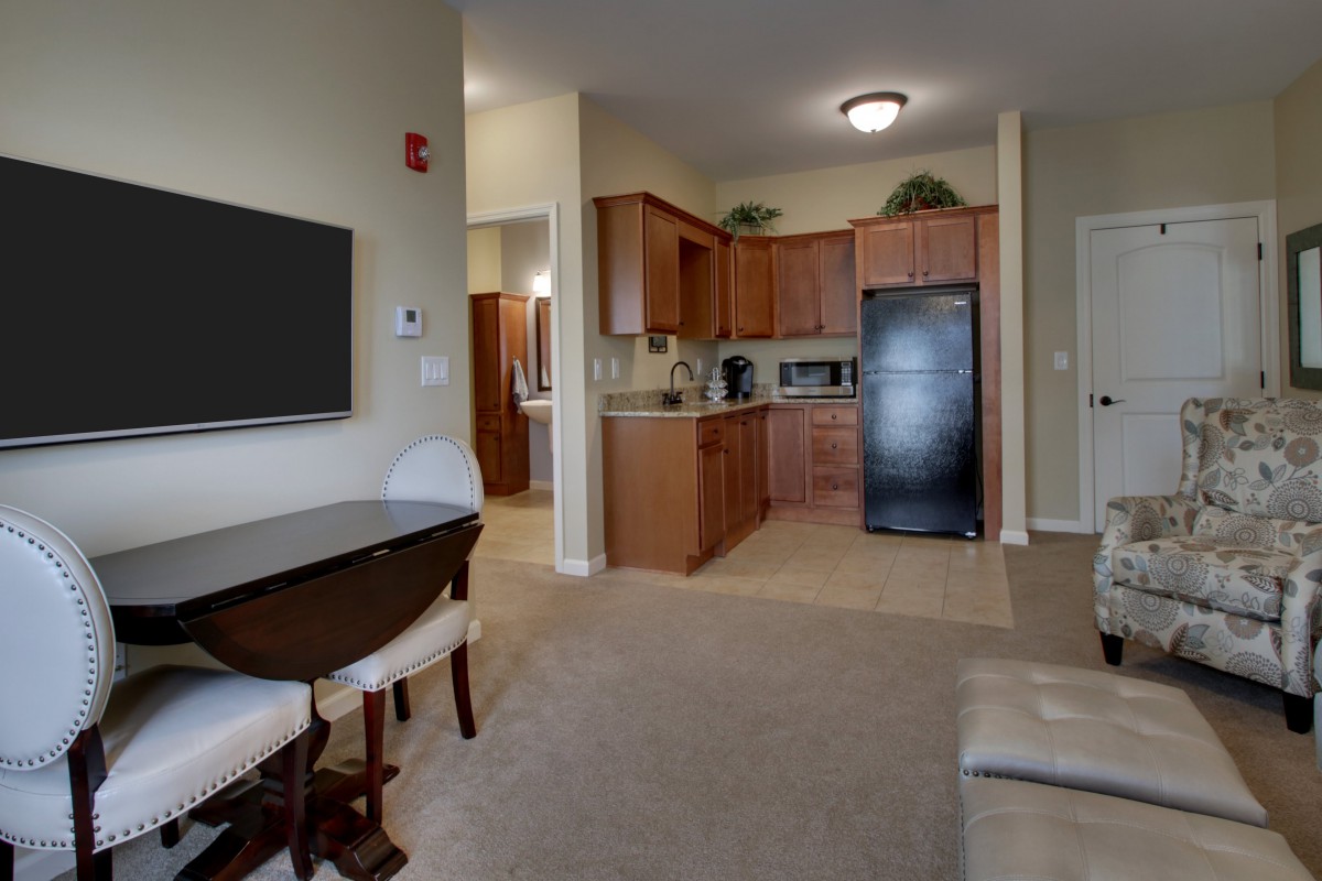A cozy apartment interior featuring a living room with a television and dining area adjacent to a modern kitchen.