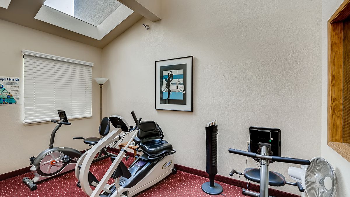 A small fitness room with exercise equipment, including stationary bikes and a wall-mounted artwork.