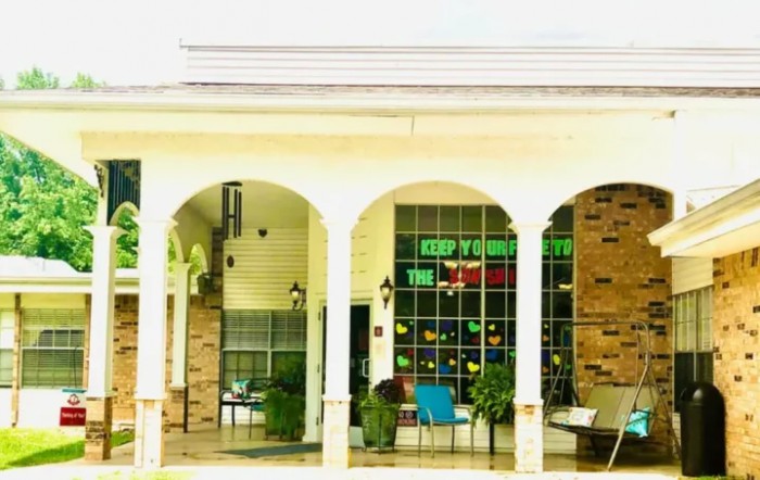 A building exterior featuring arches, columns, and a seating area.