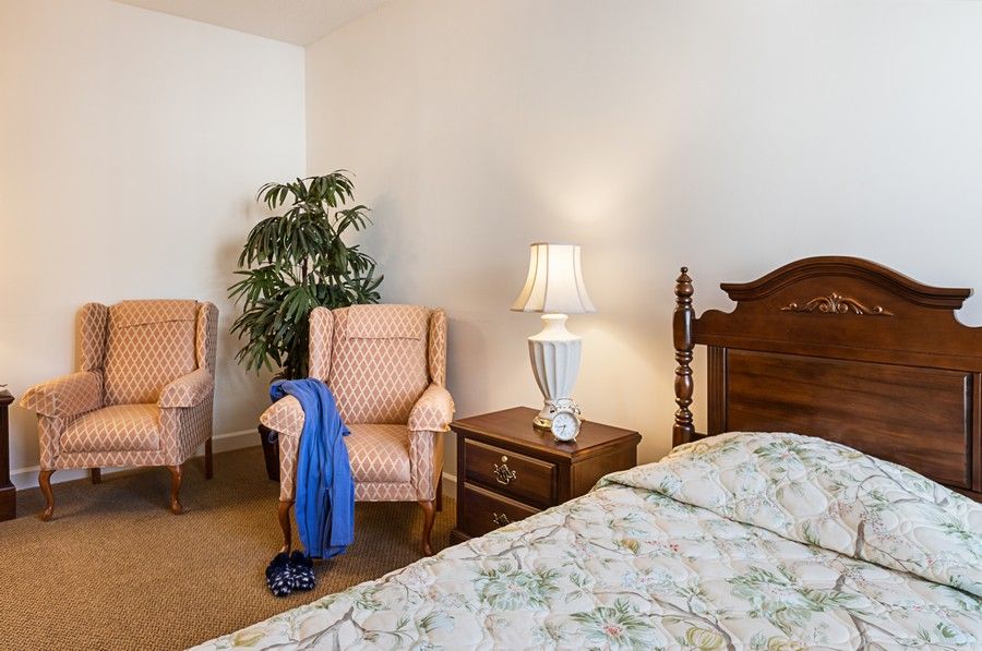 Cozy bedroom with armchairs, a bedside table, and a potted plant.