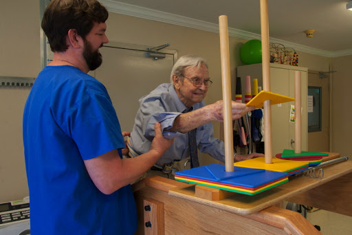 A caregiver assists an elderly person with a hands-on activity, promoting engagement and learning.