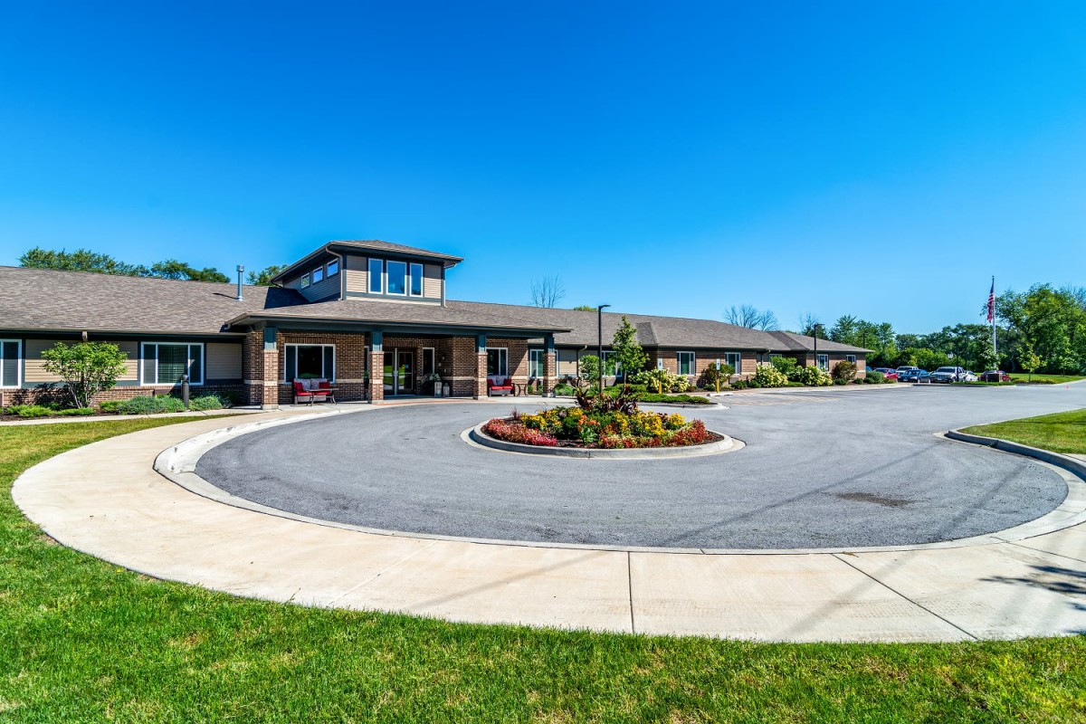 A modern building with a circular driveway under a clear blue sky.