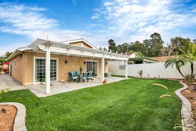 A spacious backyard with a covered patio and well-maintained lawn.