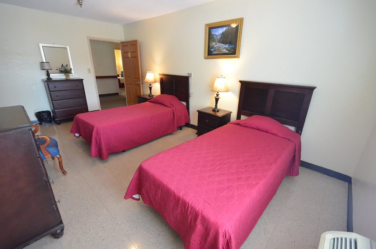 A hotel room with two twin beds and simple decor.