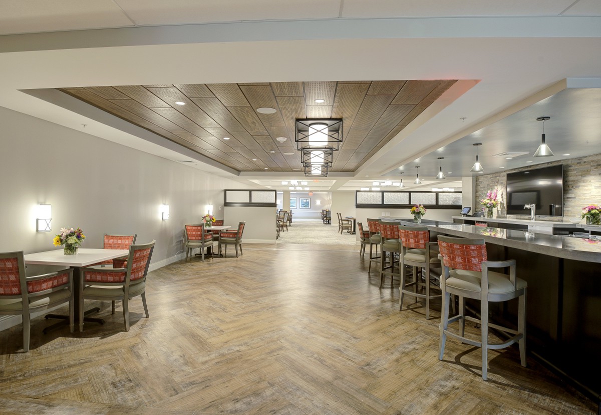 A modern restaurant interior with dining tables and bar seating.