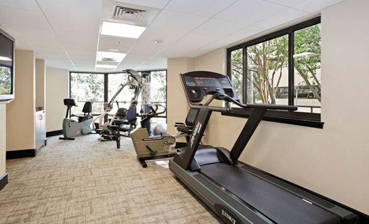 A well-lit gym featuring various exercise equipment, including treadmills and weight machines.