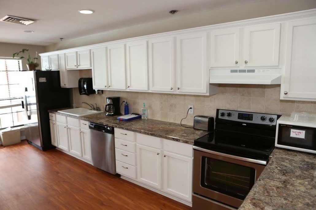A modern kitchen with white cabinets, stainless steel appliances, and granite countertops.