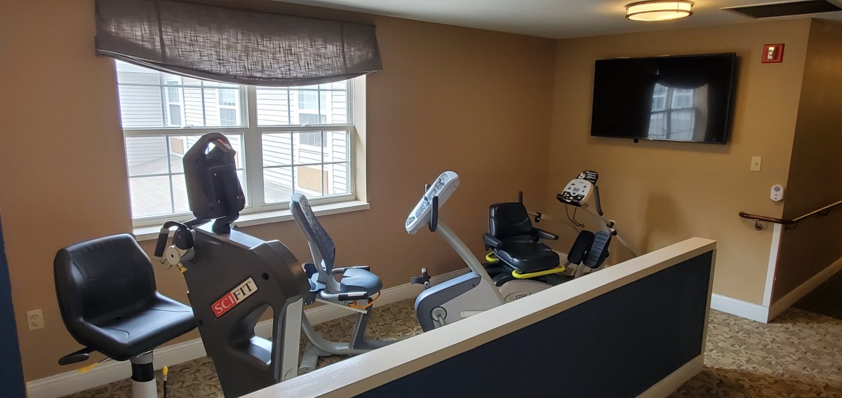 A small home gym with exercise bikes and a television.