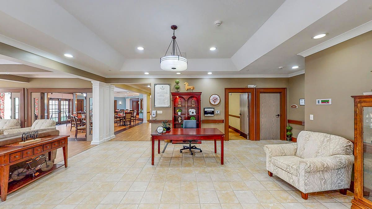 A welcoming lobby area with a central red desk, chandelier lighting, and comfortable seating.