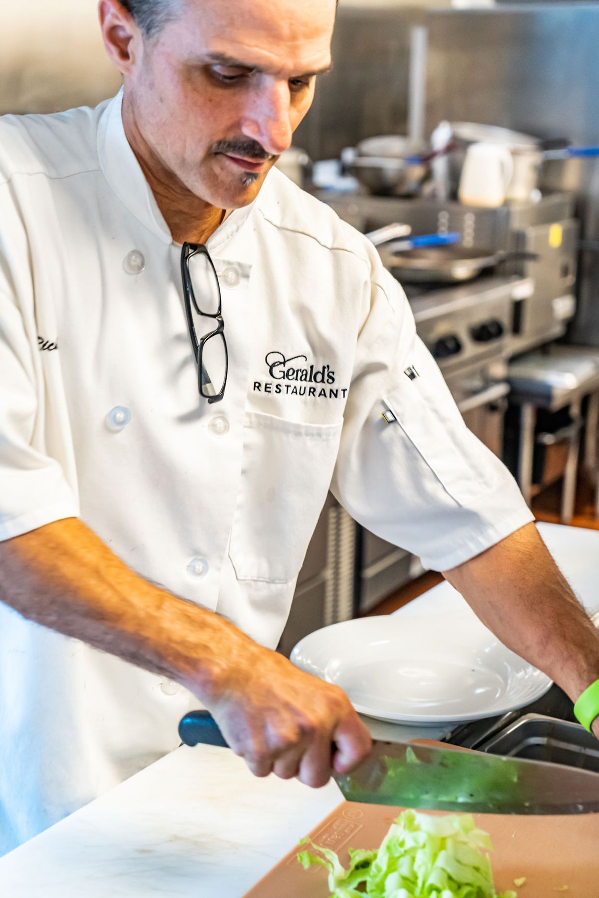 A chef in a white uniform preparing food in a professional kitchen.
