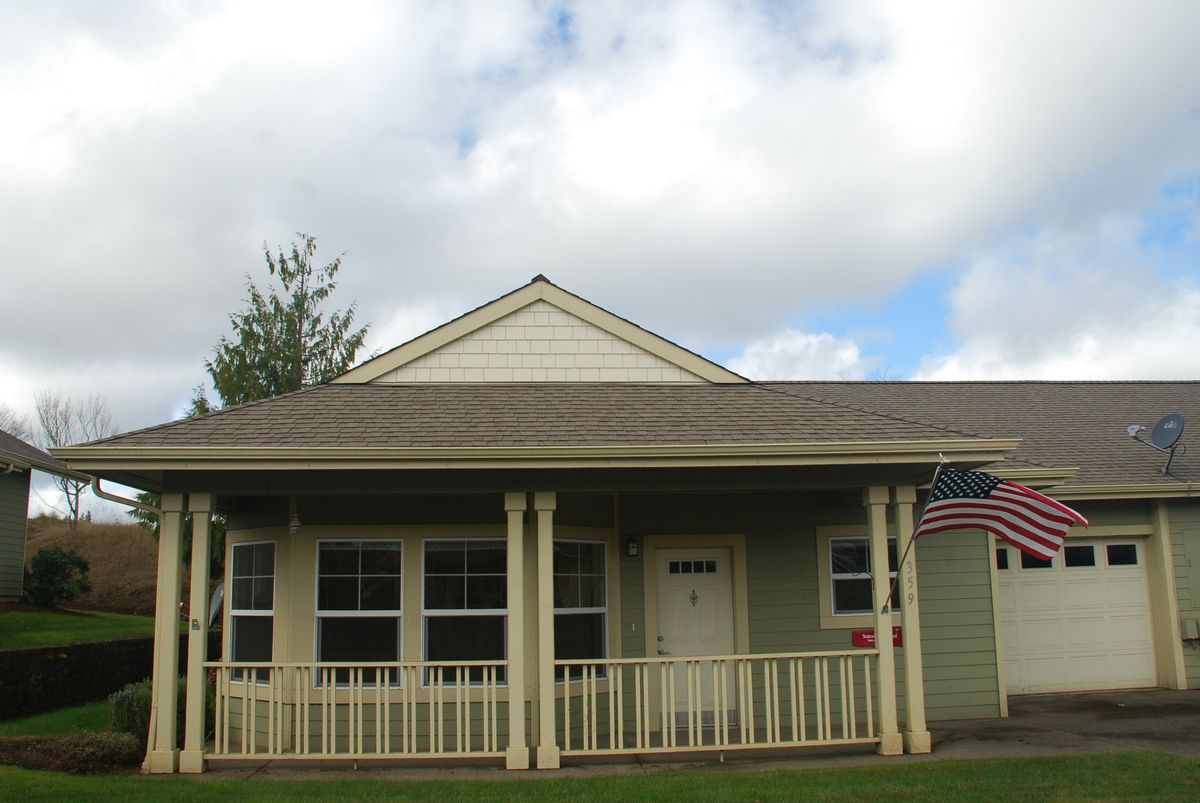 A small suburban house with a porch and an American flag.