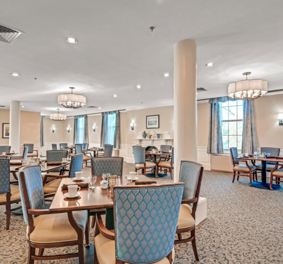 An elegant dining room with neatly arranged tables and chairs, featuring warm lighting and tasteful decor.