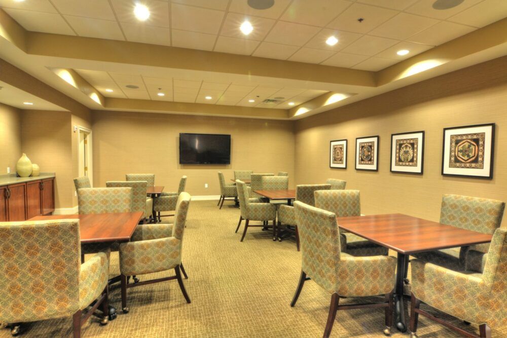 A conference room with several tables and chairs, featuring a television and artwork on the walls.