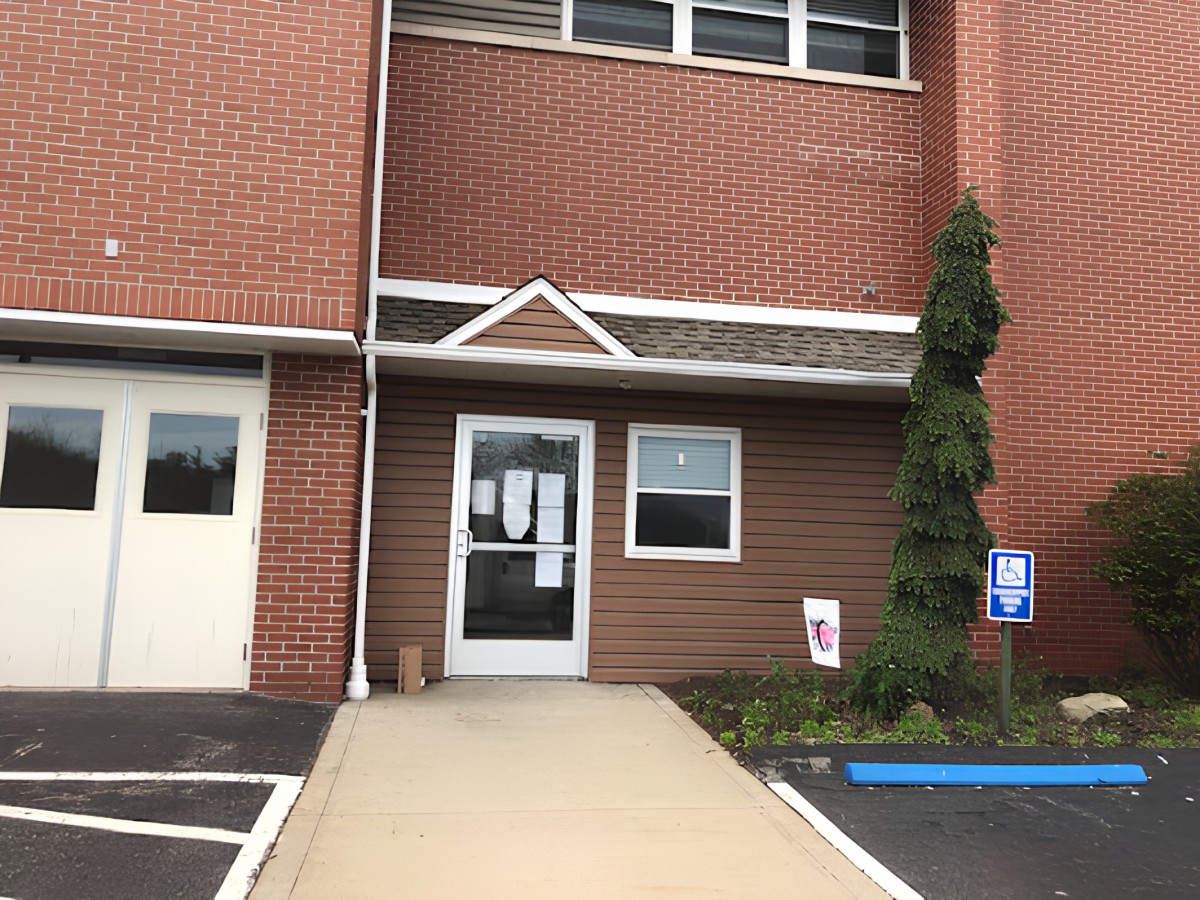 Entrance to a brick building with a parking space and sidewalk.
