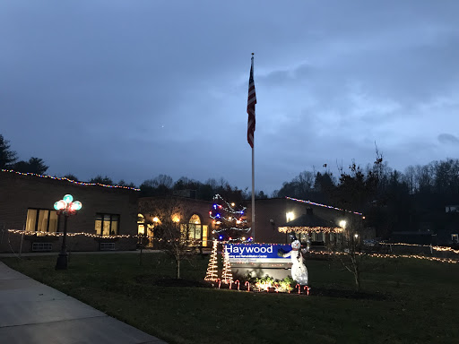 A flag stands tall amidst festive holiday decorations outside a building during the evening.