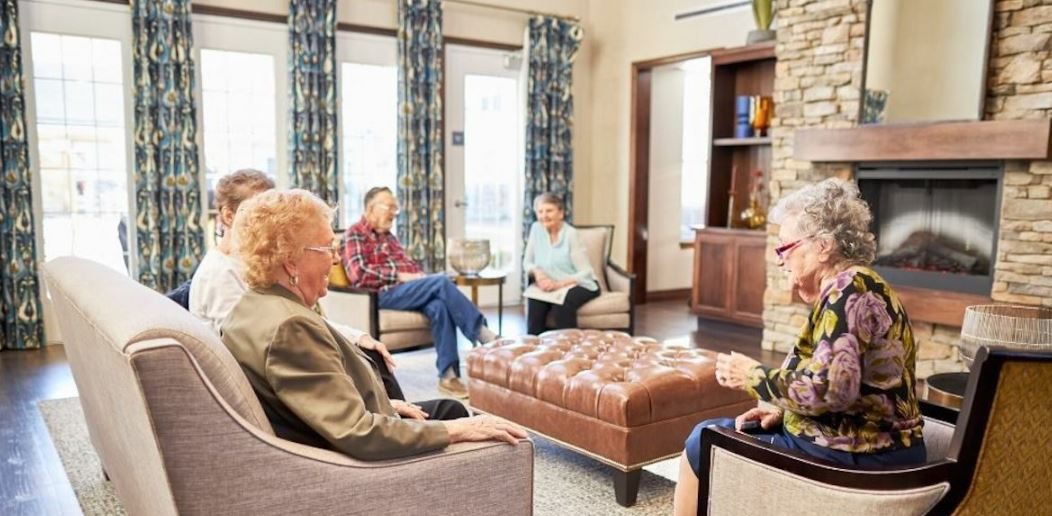 A group of seniors engaging in a conversation while seated in a cozy room.