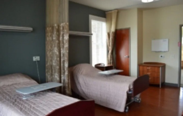 A hospital room with two beds and privacy curtains.