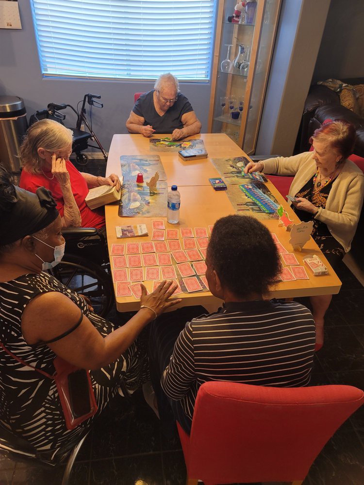 A group of elderly individuals gathered around a table playing cards.