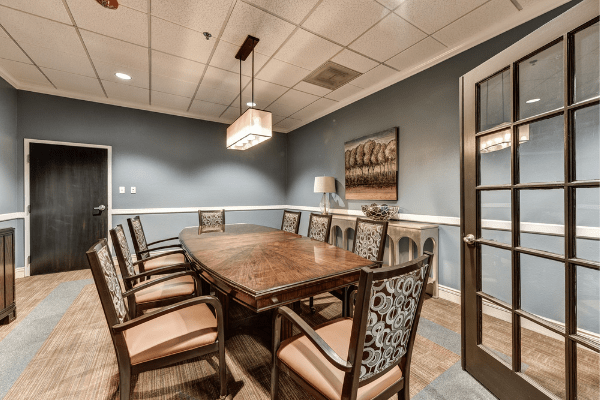 A well-furnished conference room with a wooden table and upholstered chairs, featuring elegant dcor.