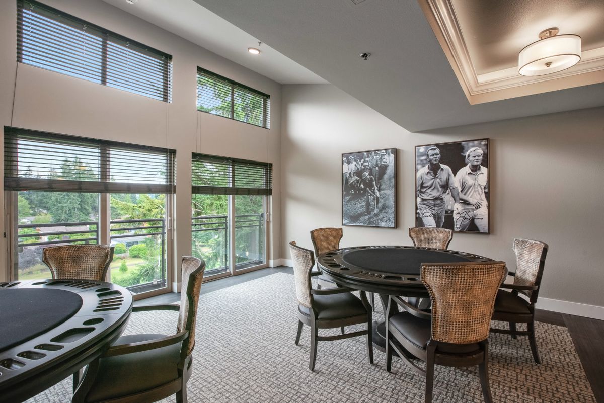 A modern dining room with large windows, stylish chairs, and artwork on the walls.