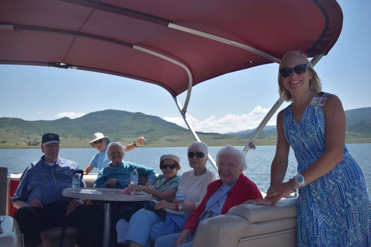 A group of people enjoying a sunny day on a boat with scenic mountain views.