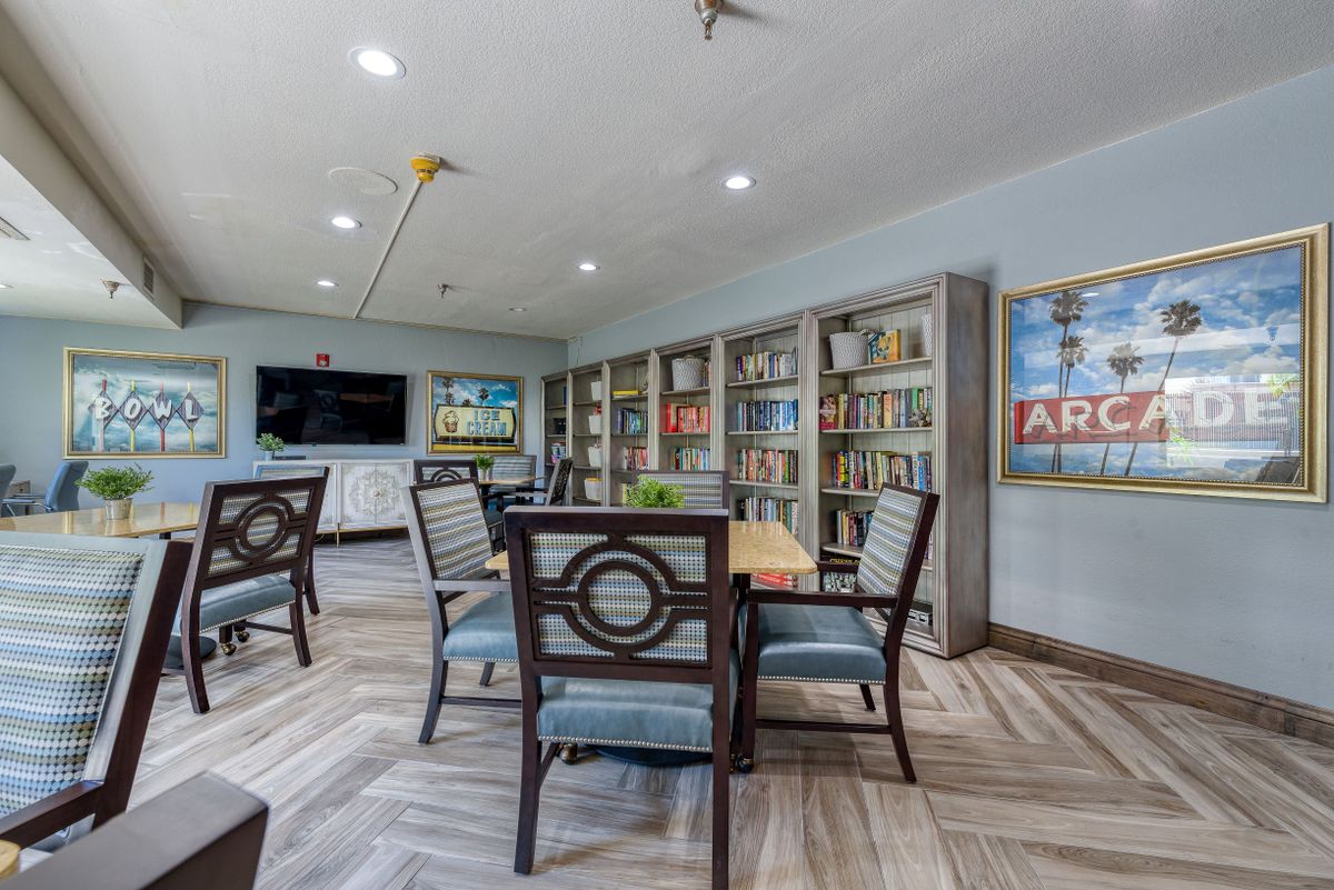 A modern library interior with bookshelves, tables, and chairs arranged for reading and study.