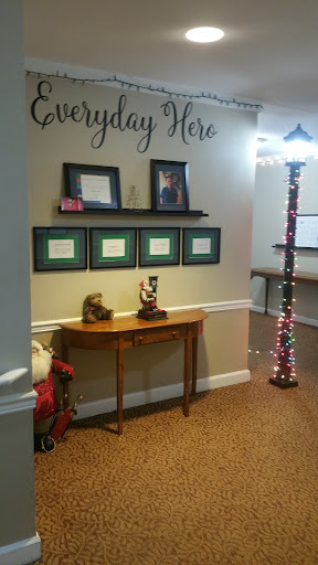 A cozy entrance area featuring framed documents, a decorative table, and festive lighting.