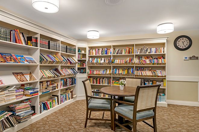 A cozy library with bookshelves, a table, and chairs for reading.