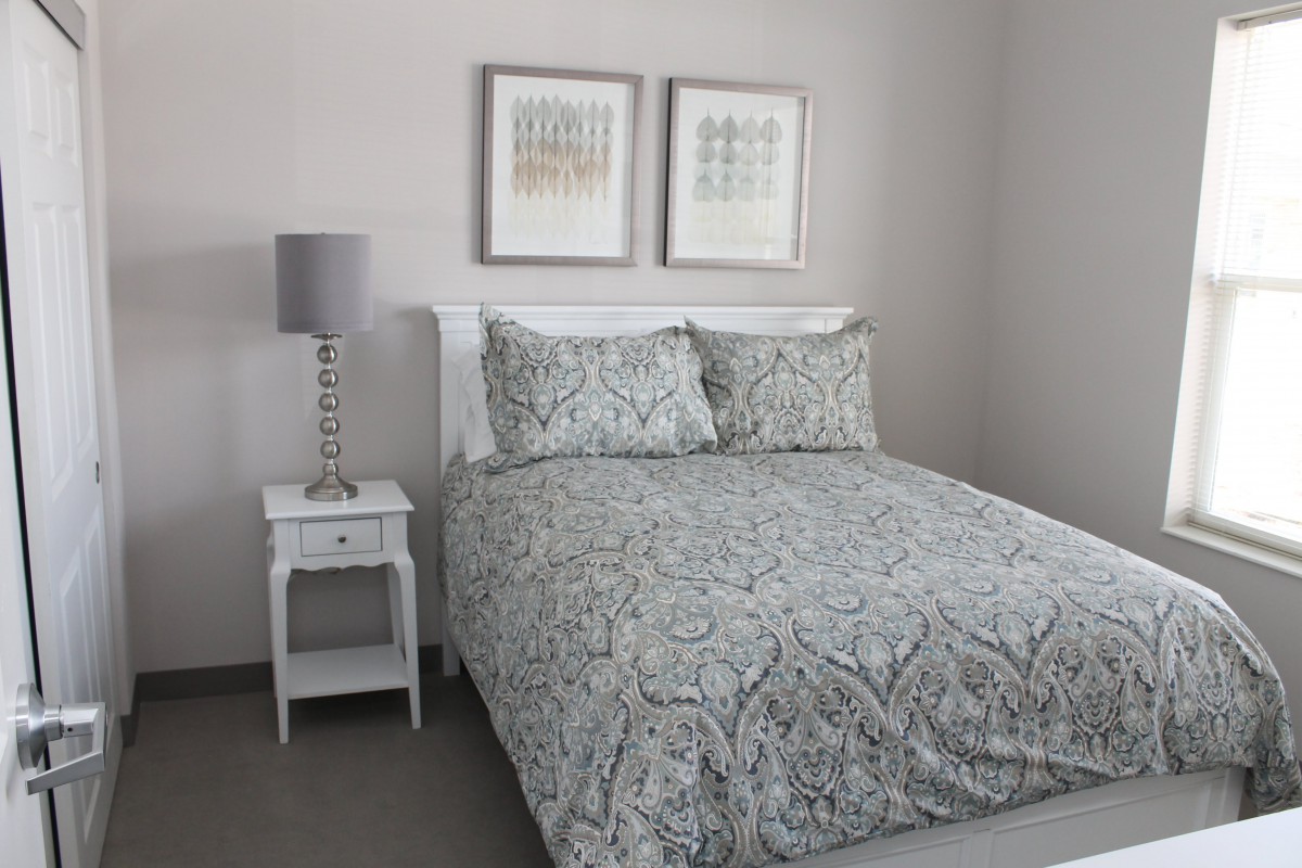 A neatly arranged bedroom with a patterned duvet, bedside table, and lamp.