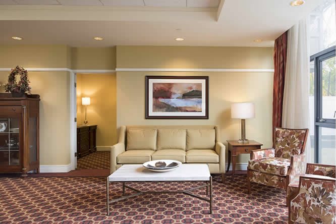 A cozy living room with a sofa, coffee table, lamp, and wall art.
