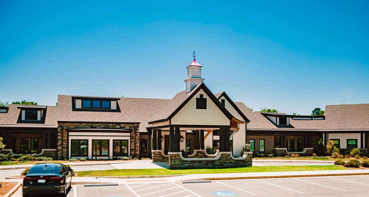 A modern building with a pitched roof and an entrance under a clear blue sky.