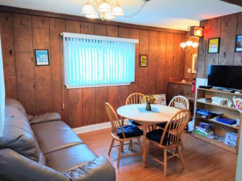 A cozy living and dining area featuring wood paneling, a comfortable couch, and a round dining table with chairs.