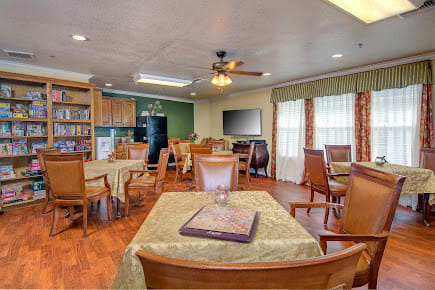 A cozy dining area with wooden tables and chairs, adjacent to a kitchen.