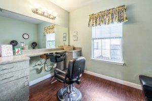 A well-lit hair salon with a barber chair and large mirror.