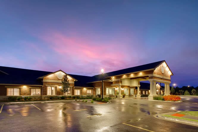 A well-lit building with a parking lot under a colorful evening sky.