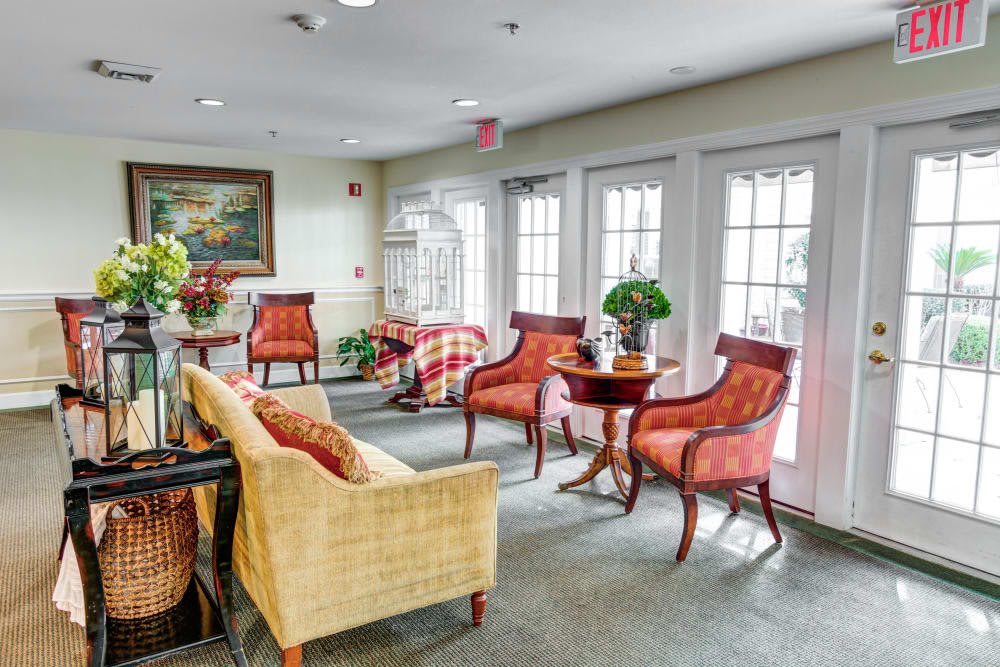 A cozy and elegantly furnished living room with chairs, a sofa, and tables arranged near large windows.