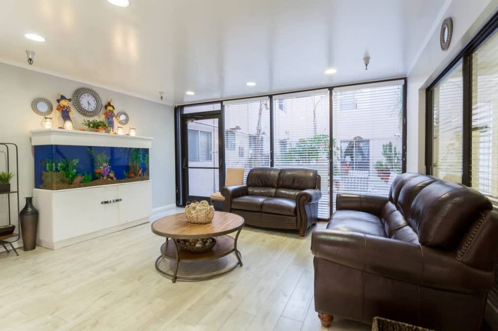 A modern living room with leather sofas, a round coffee table, and a wall-mounted television.