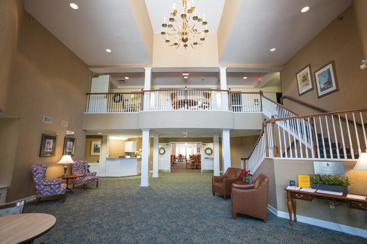 A spacious and elegant lobby with a grand chandelier, staircase, and modern furnishings.