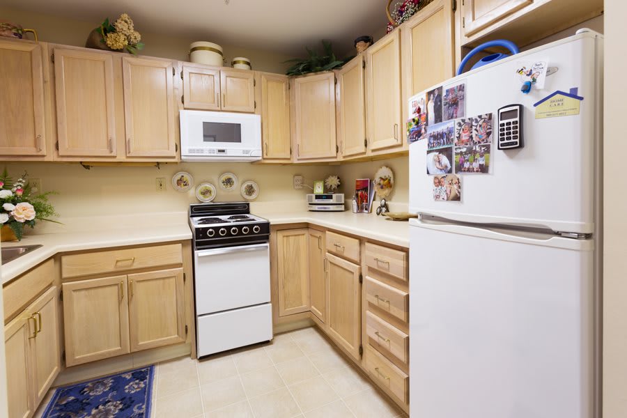 A cozy kitchen with wooden cabinets, equipped with a stove, microwave, and refrigerator.